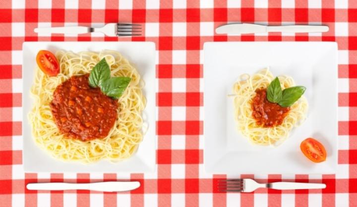 két különböző méretű adag spagetti fehér tányéron